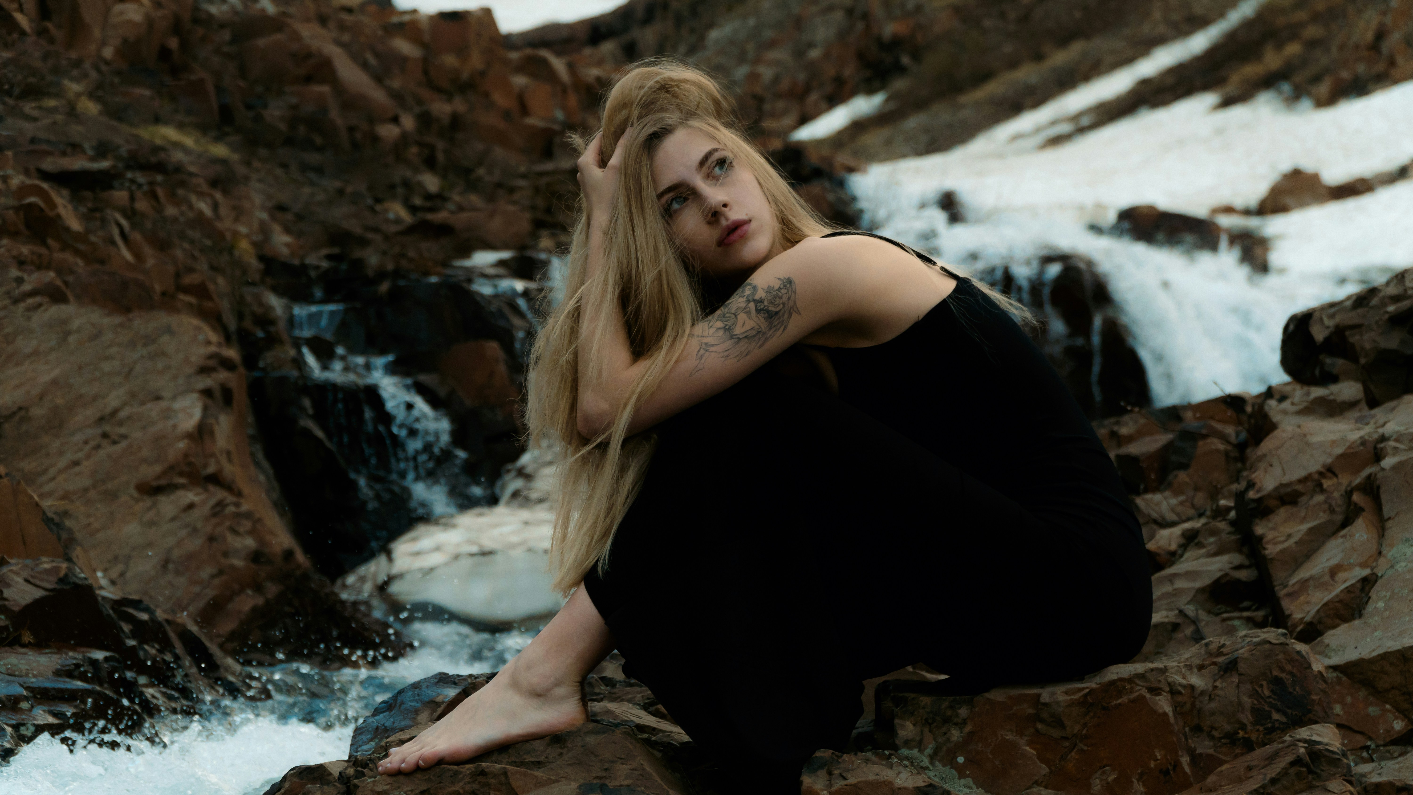 A woman sitting on a rock next to a waterfall