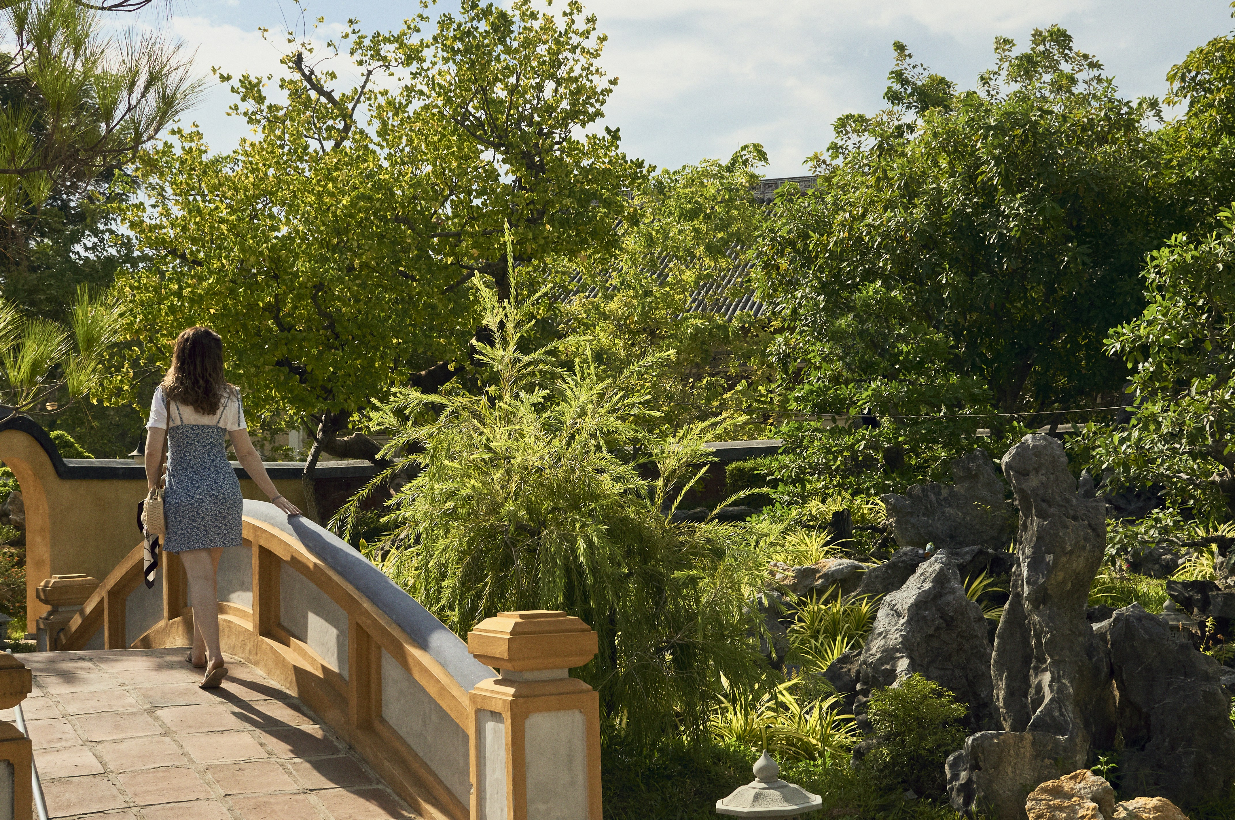 A woman standing on a wooden bridge over a pond
