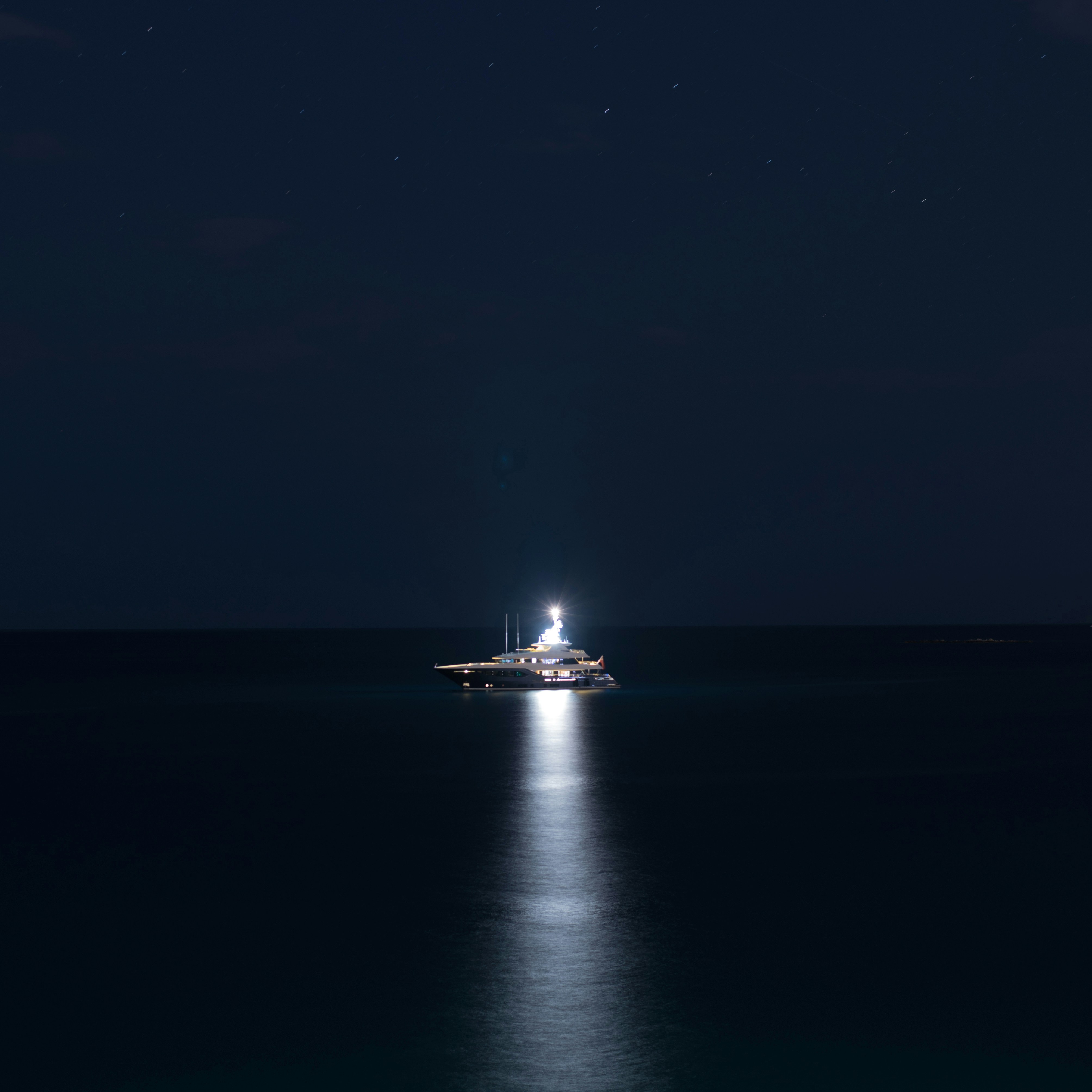 A boat floating in the middle of the ocean at night