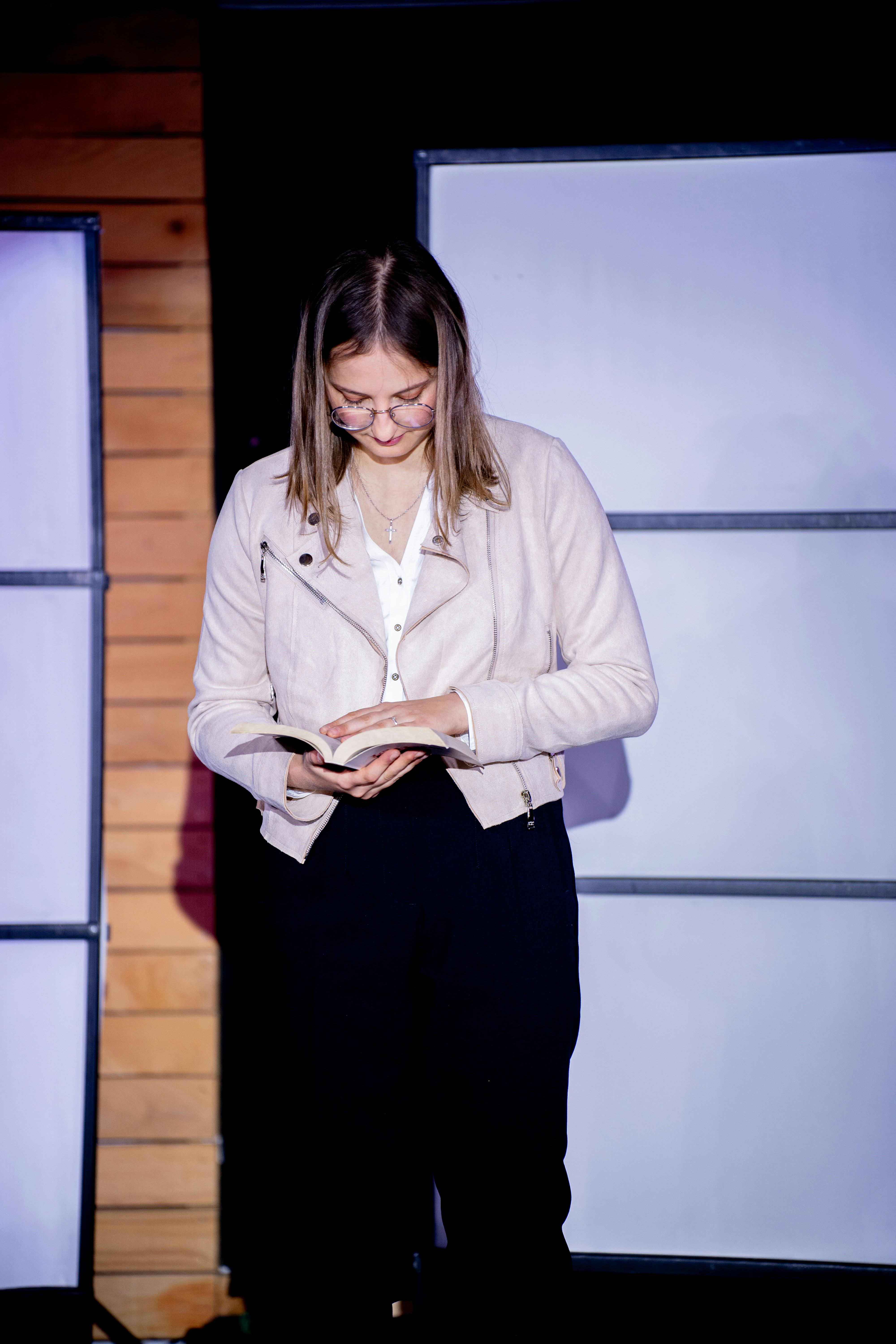 A woman standing in front of a wall holding a book