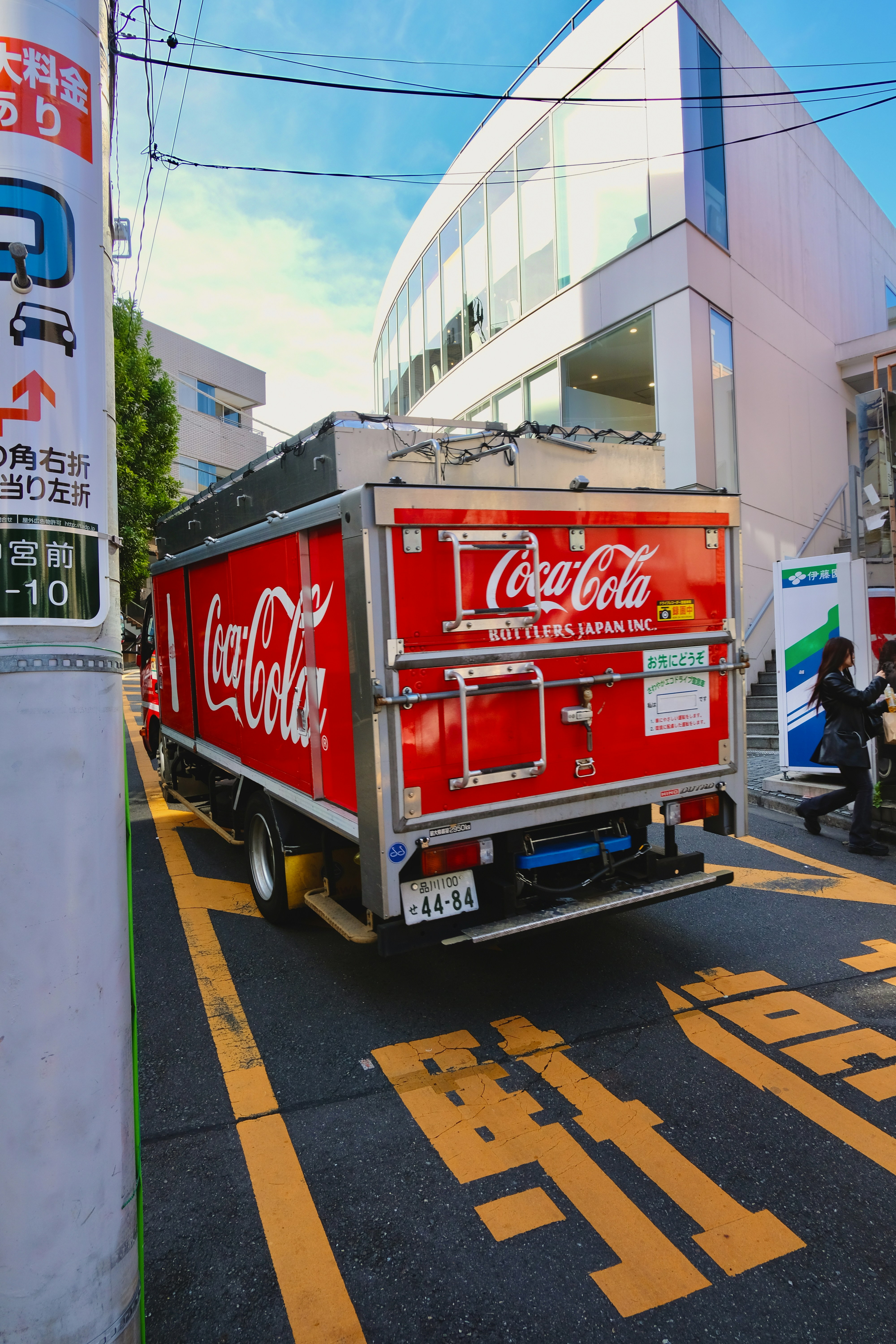 A red truck driving down a street next to a tall building
