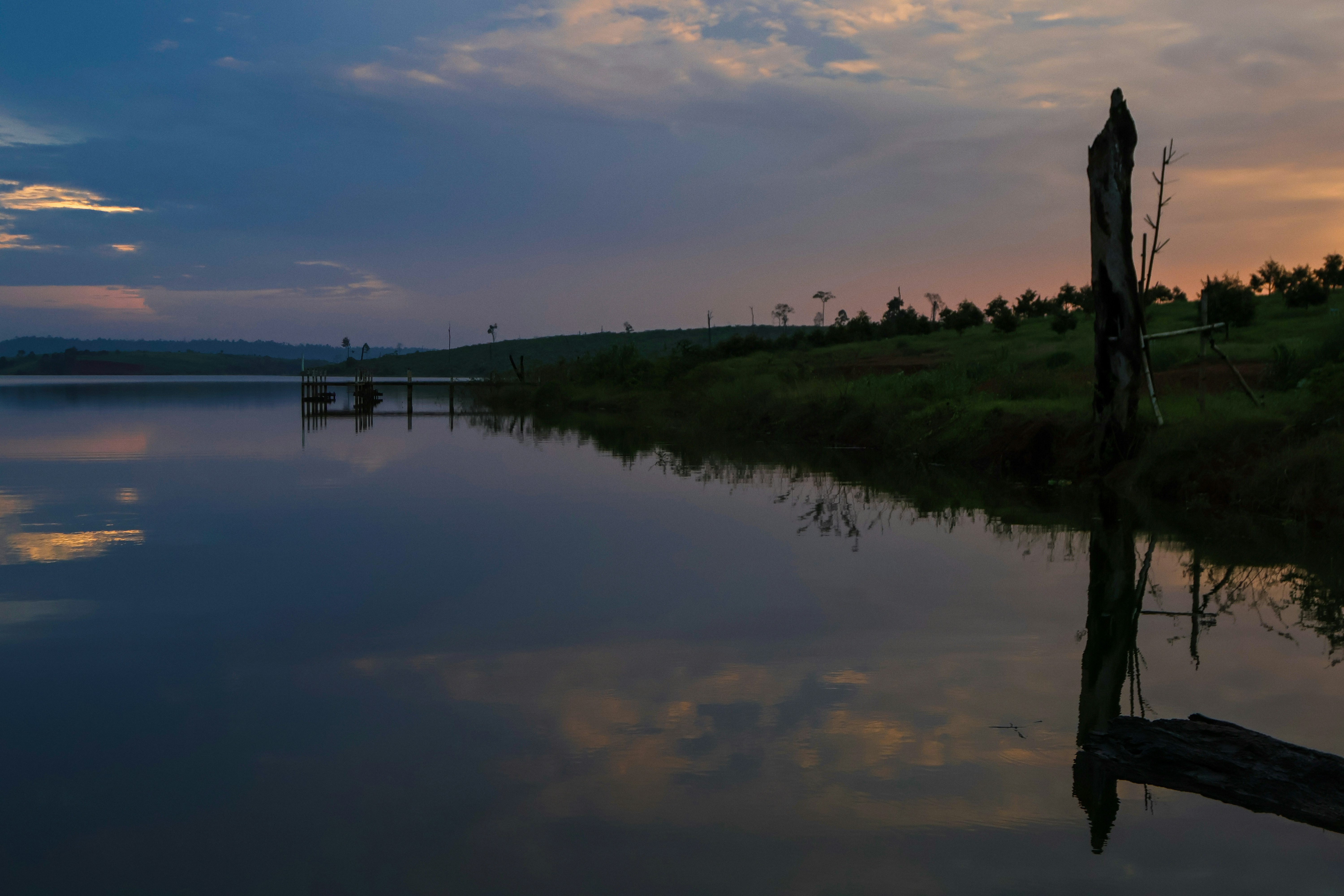 A body of water with a tree stump in the foreground
