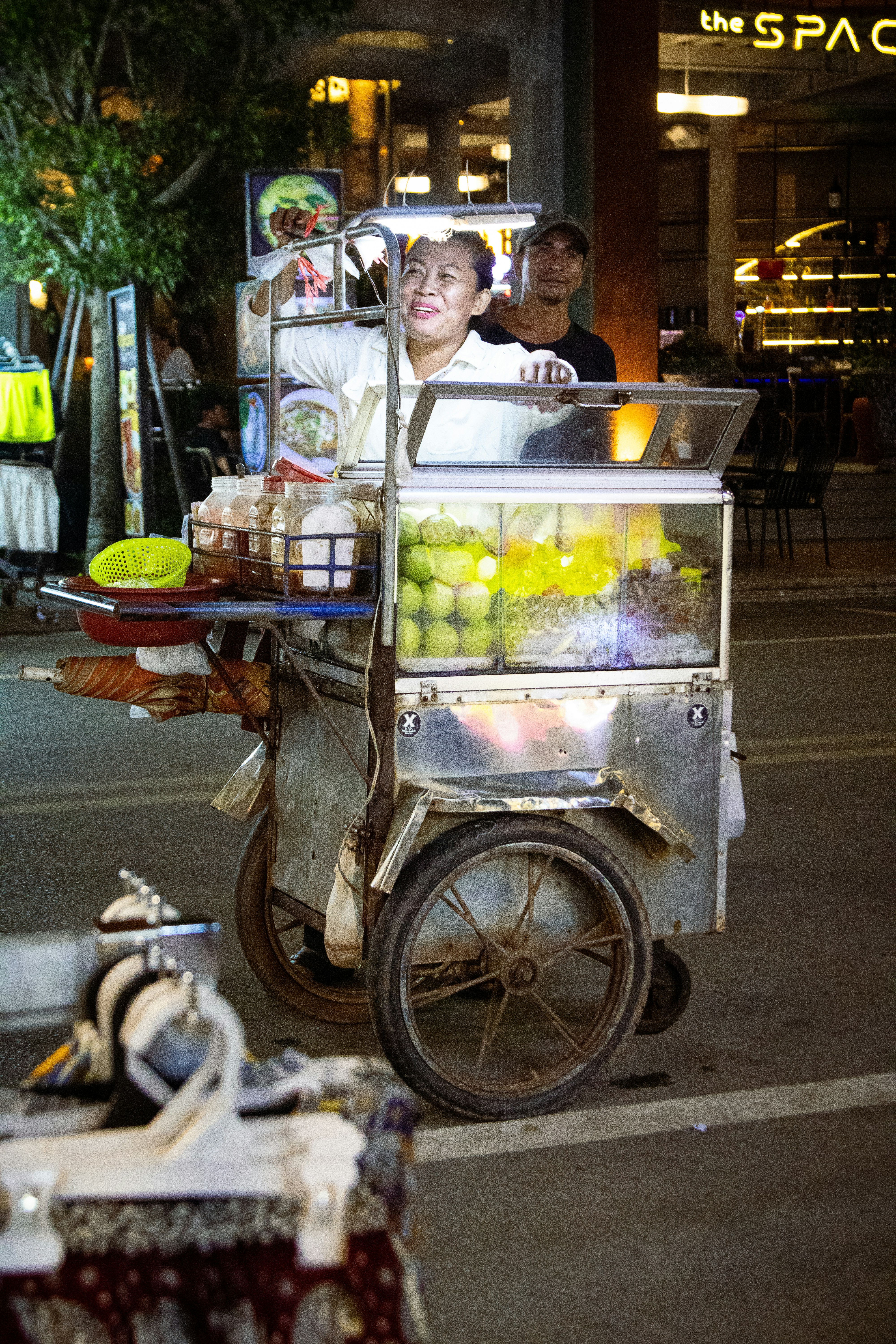 A man pushing a cart full of food down a street