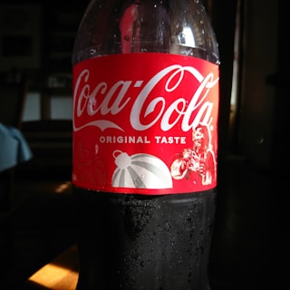 A bottle of coca cola sitting on top of a table