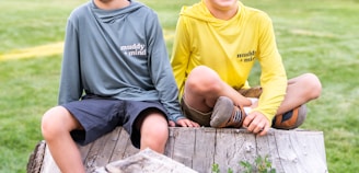 A couple of kids sitting on top of a wooden bench