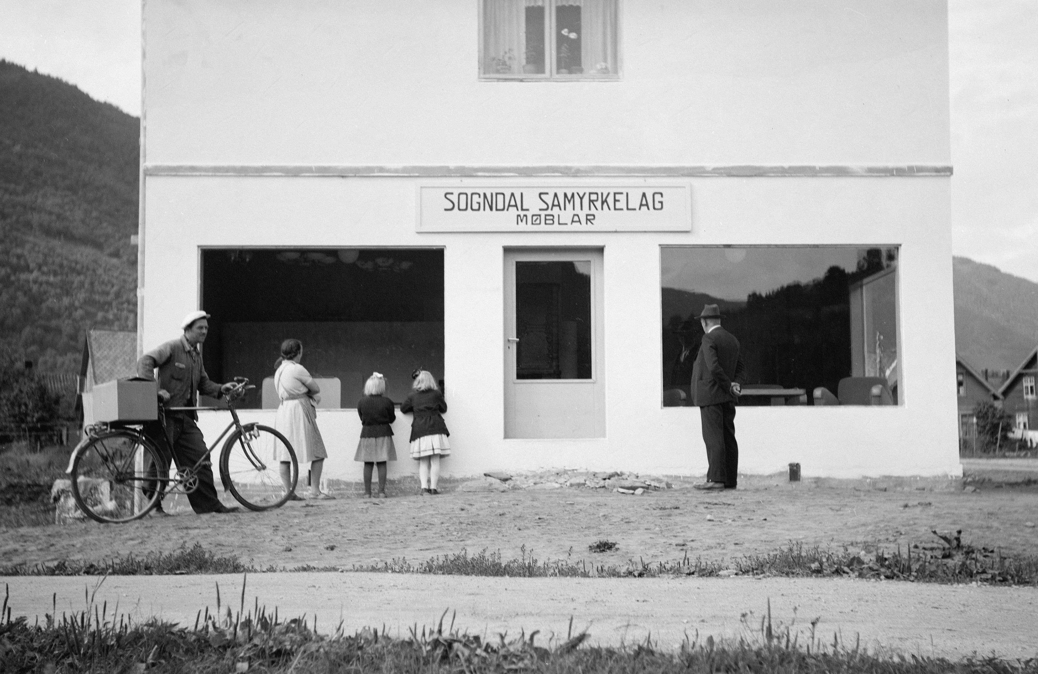 Pessoas se reuniram do lado de fora de uma loja com uma bicicleta.