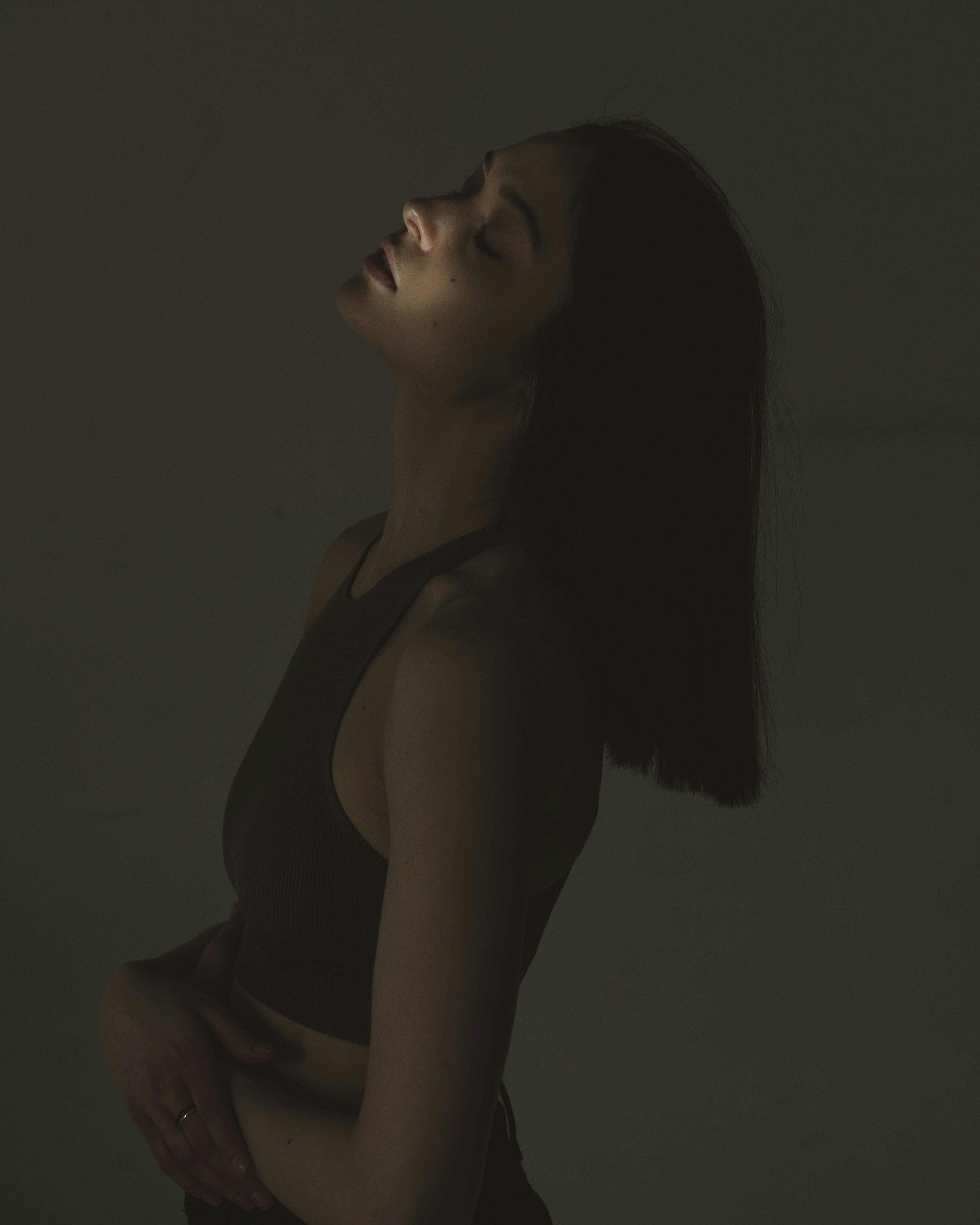 A woman standing in a dark room with her hands on her hips