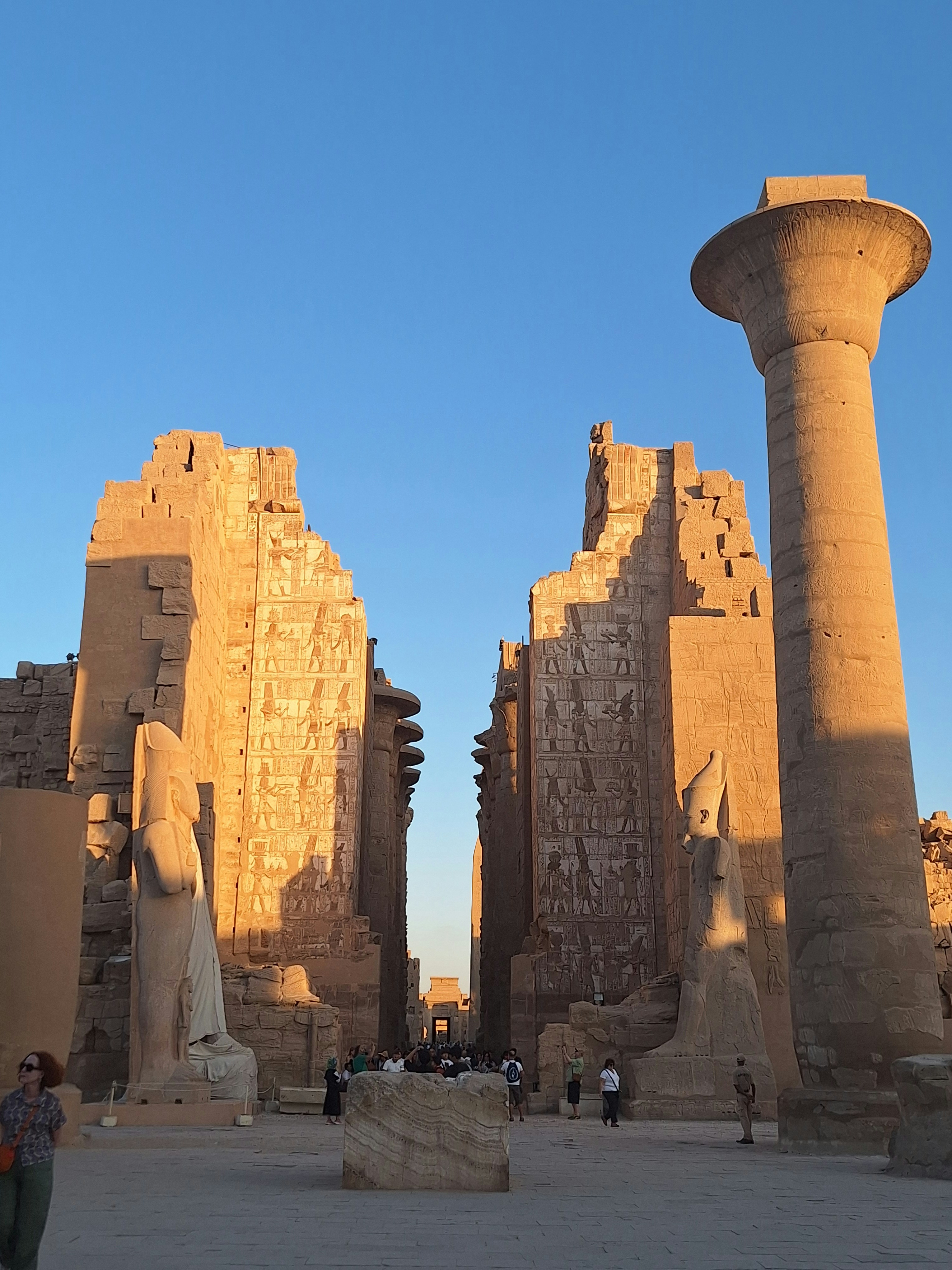 Ancient Egyptian temple walls with hieroglyphic battle scenes carved in stone, golden sunset light