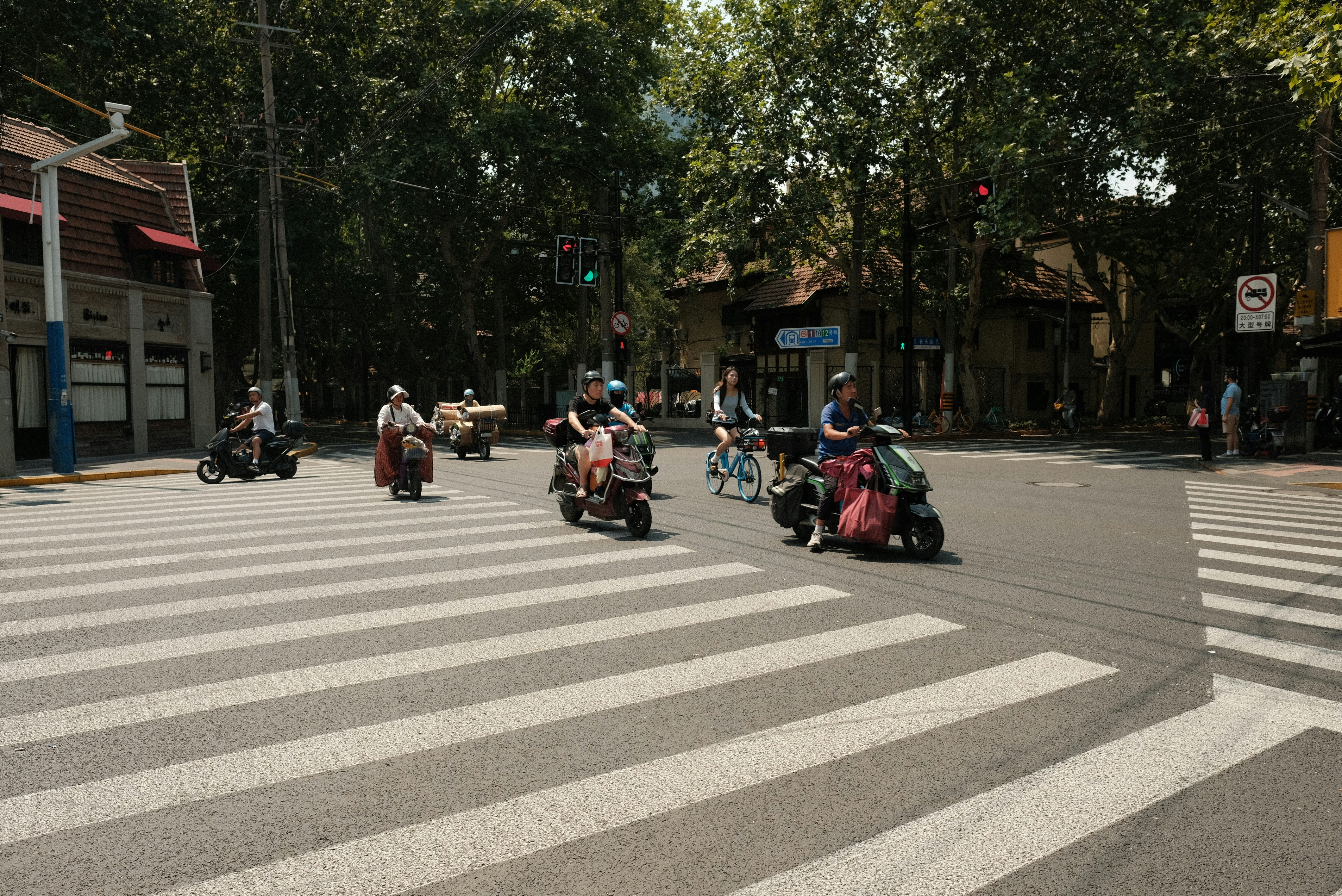 A group of people riding scooters down a street