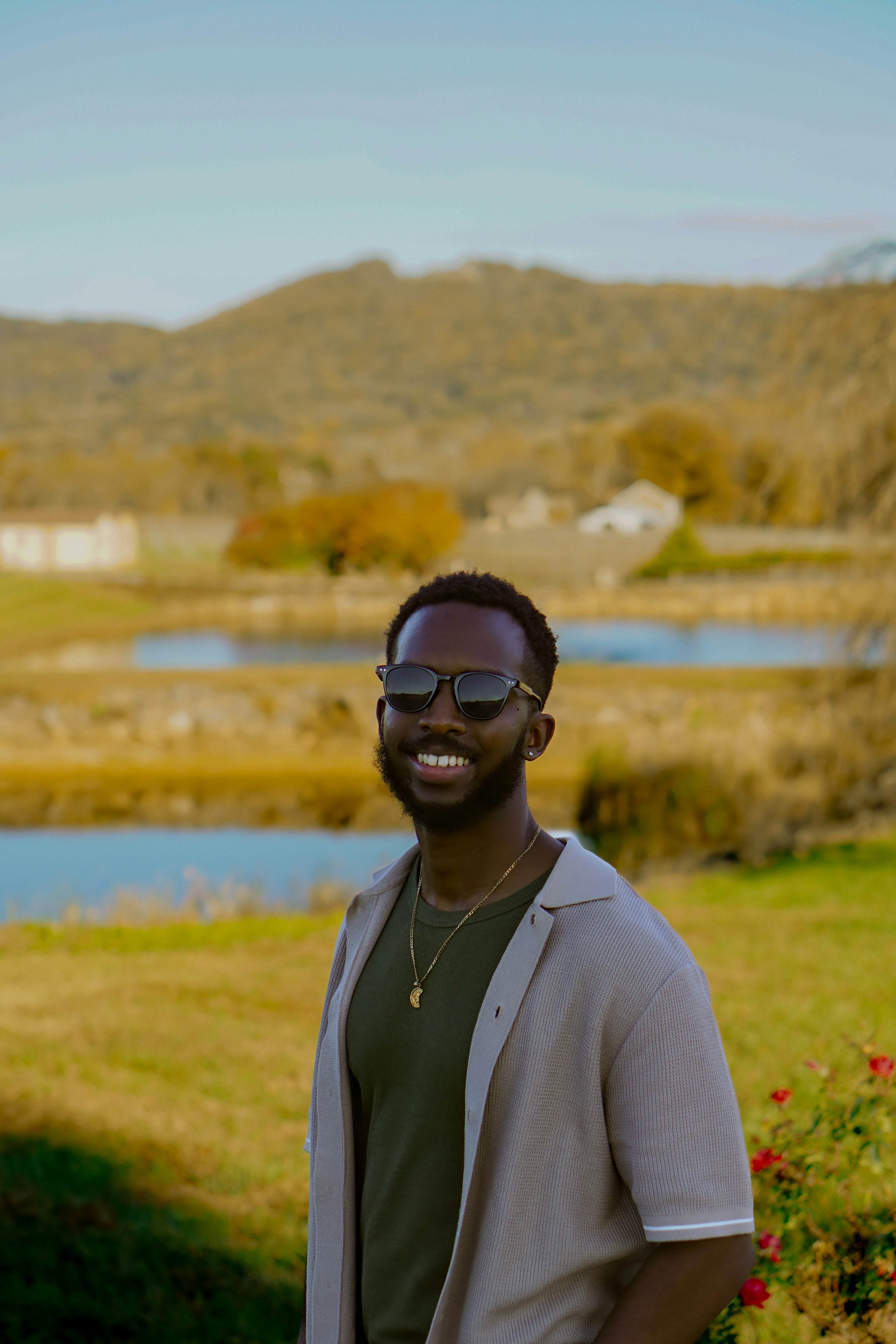 African American man in green shirt smiling outdoors with natural background