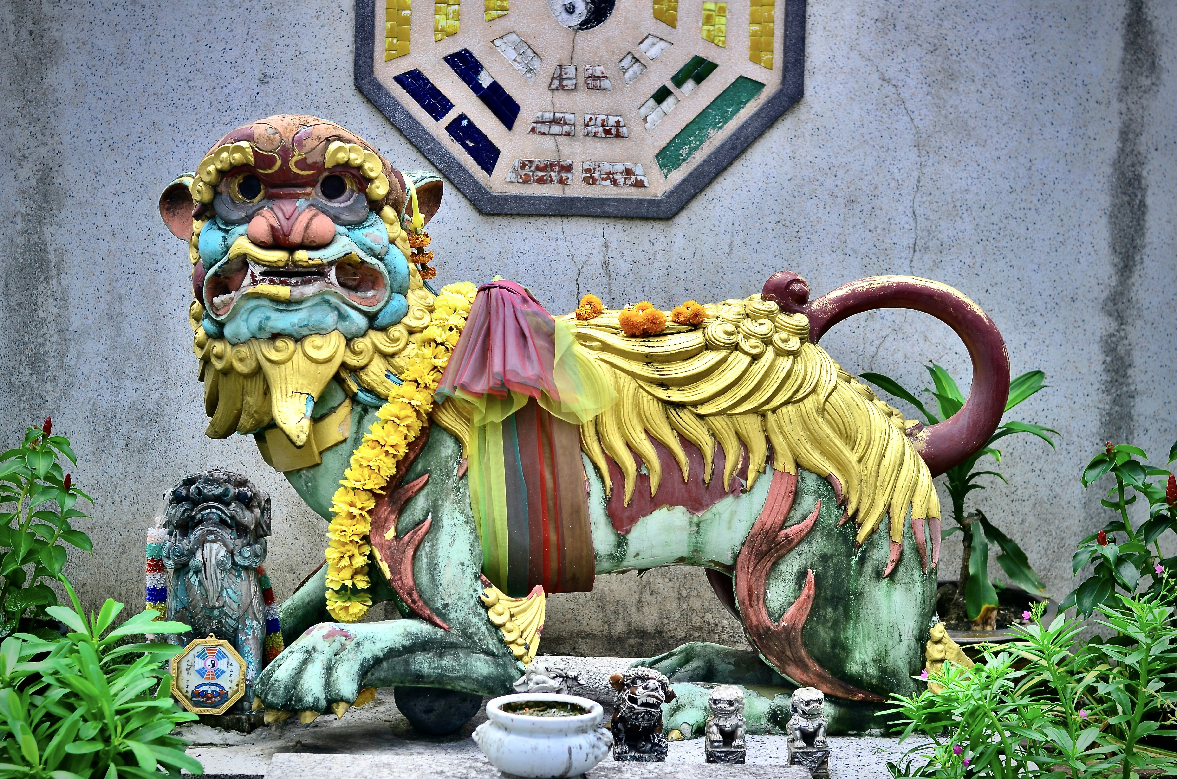 A lion statue in front of a wall with a clock above it