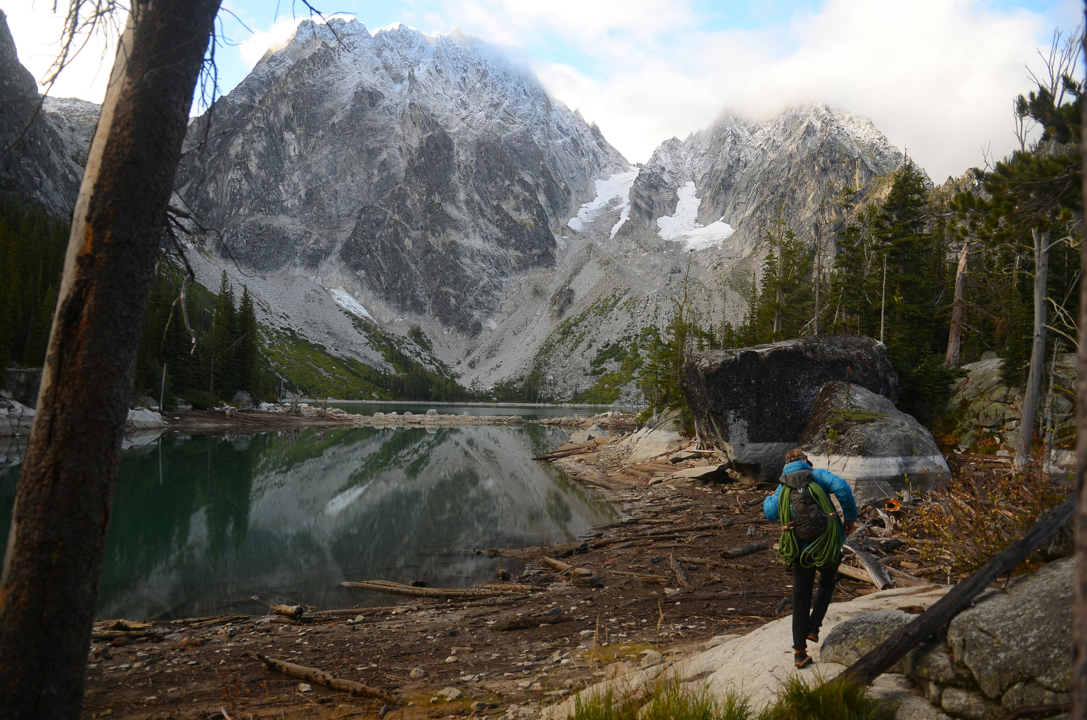 A person with a backpack walking on a path near a lake
