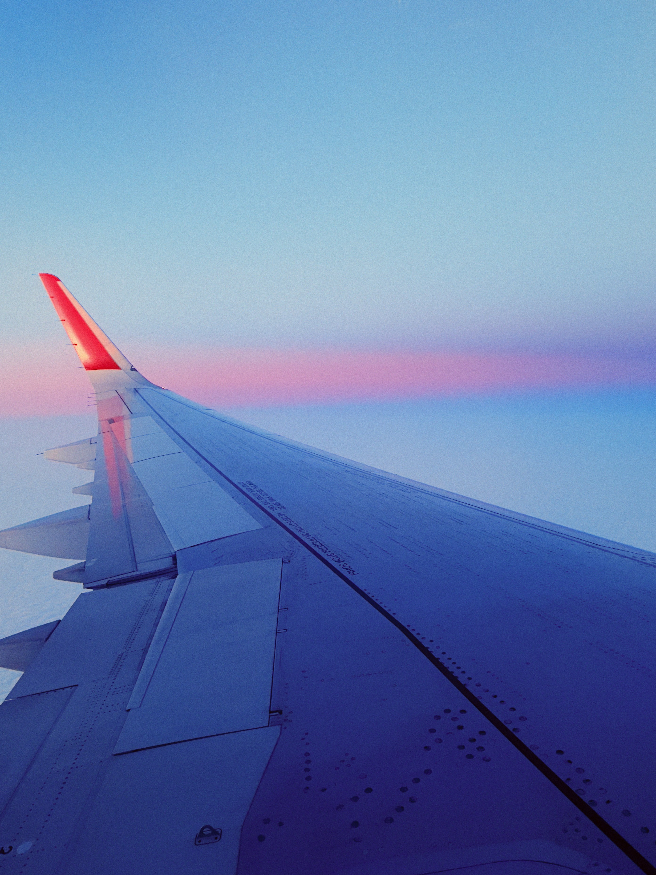 The wing of an airplane flying over the ocean photo – Free Sunset Image ...