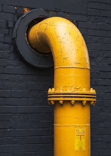 A yellow fire hydrant next to a black brick wall
