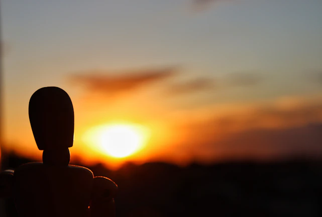 The sun is setting behind a statue of a person