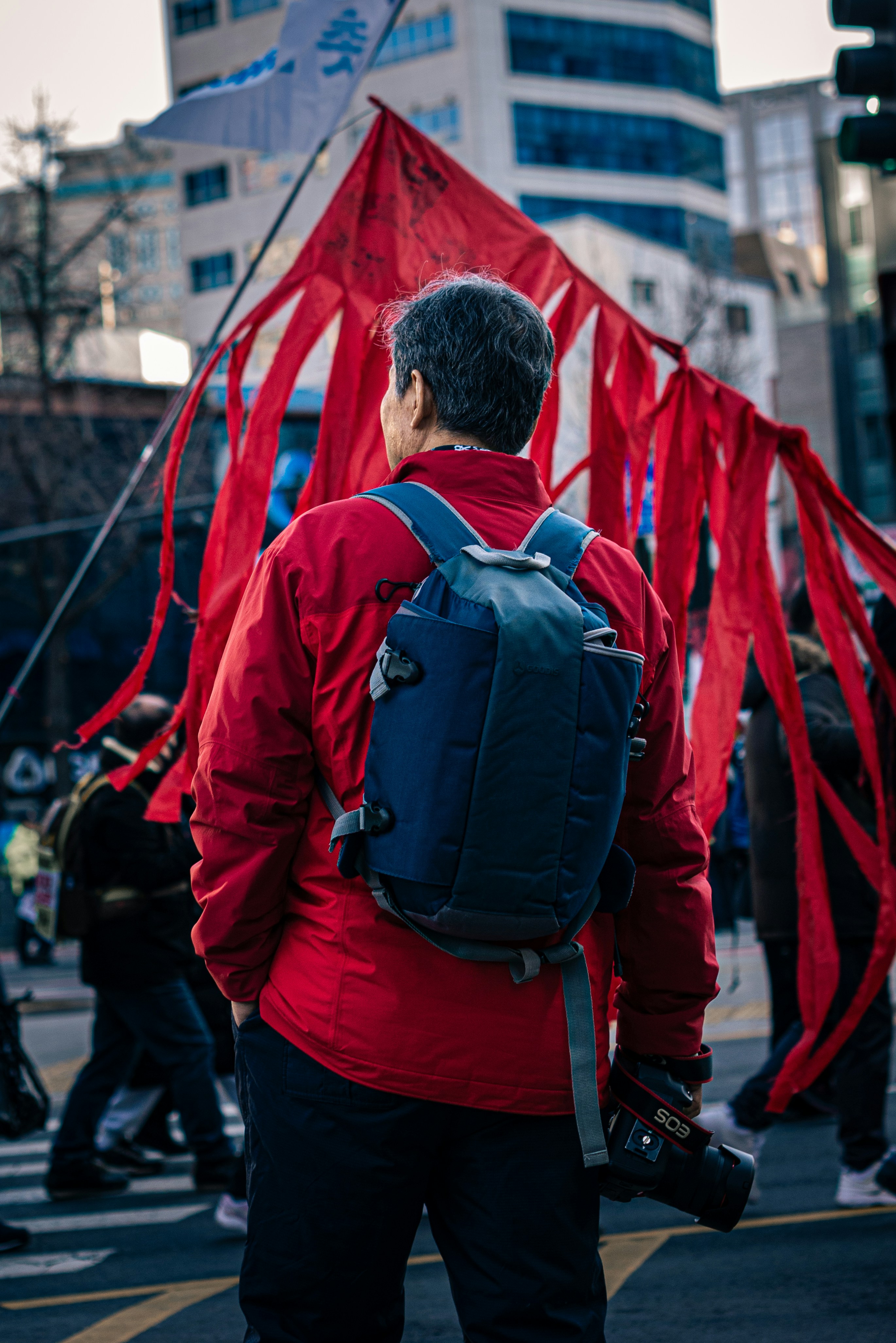 A man in a red jacket with a blue backpack
