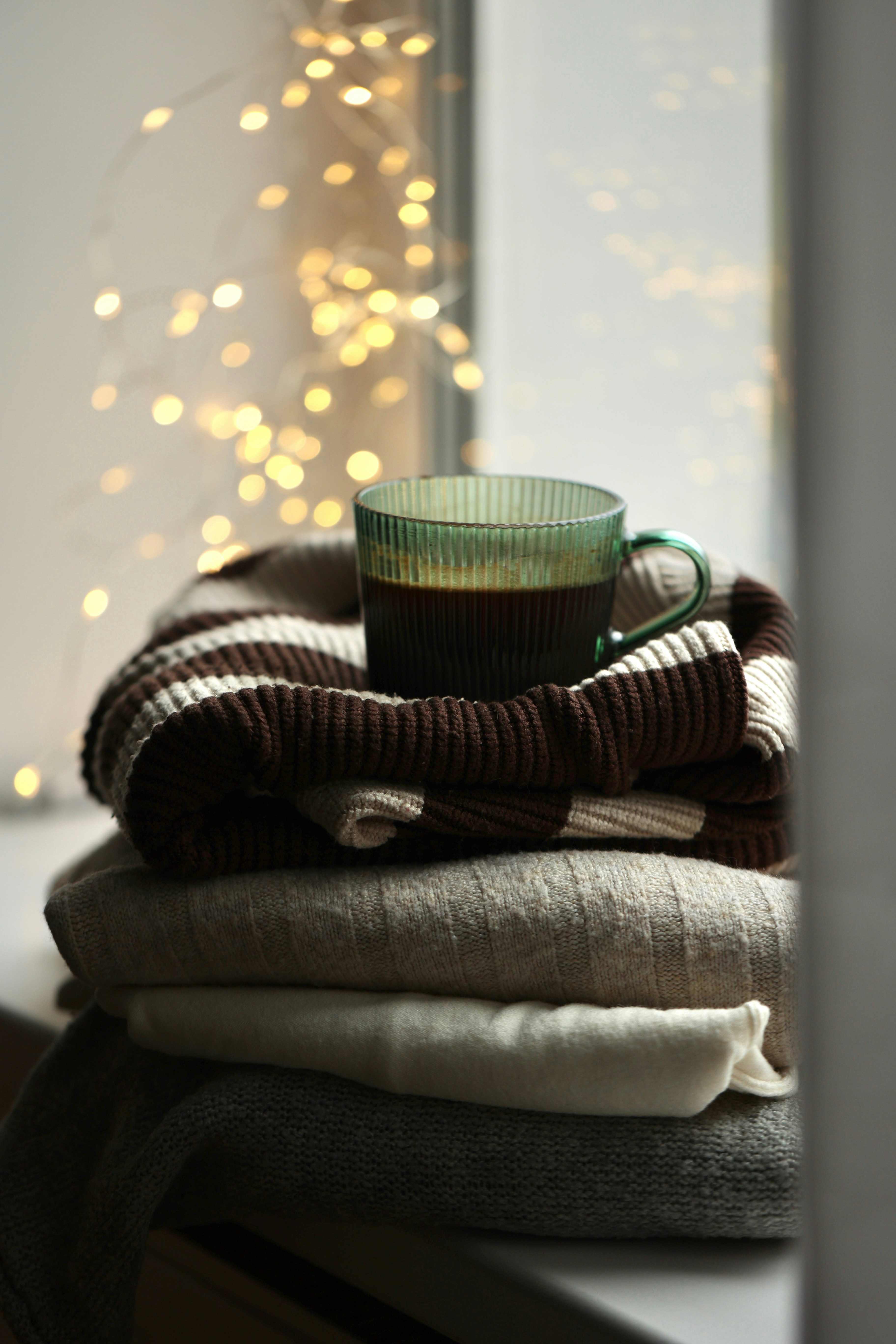 A stack of folded clothes sitting on top of a window sill