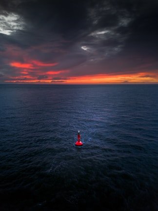 A red buoy floating in the middle of a large body of water