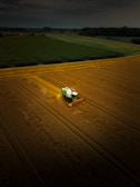 A green and white truck driving across a field