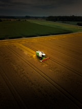 A green and white truck driving across a field