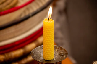 A yellow candle sitting on top of a metal container