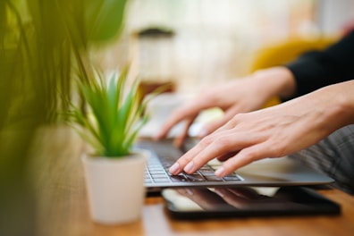 A person typing on a laptop on a wooden table