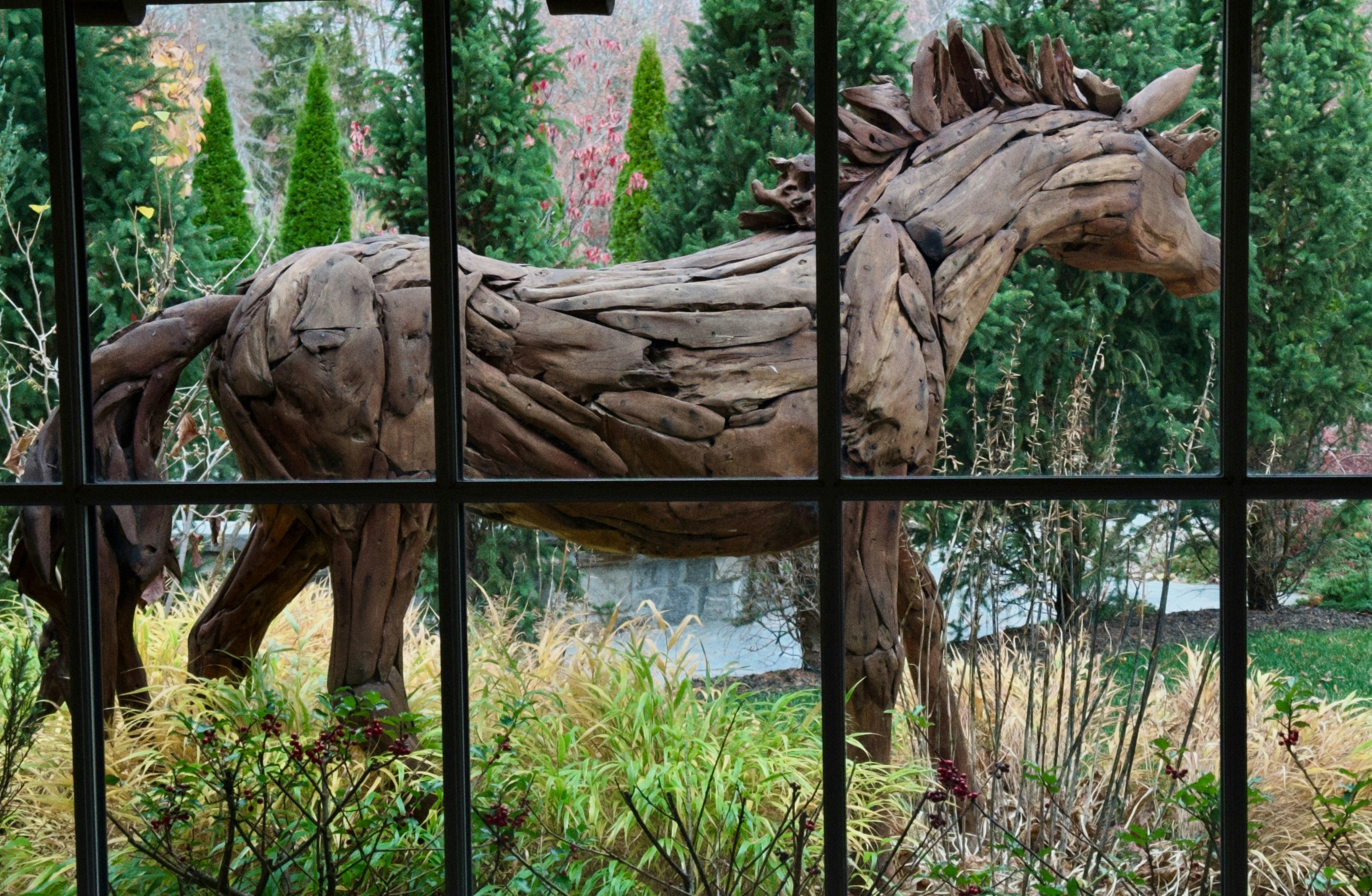 A horse made out of wood is seen through a window