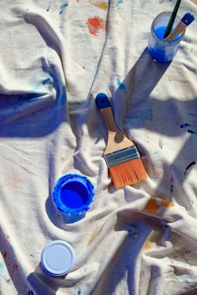 A table topped with paint and brushes on top of a white cloth