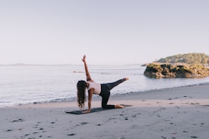 A woman doing a yoga pose on the beach