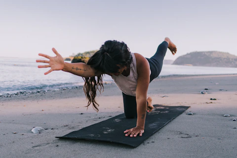 A woman doing yoga on a mat on the beach