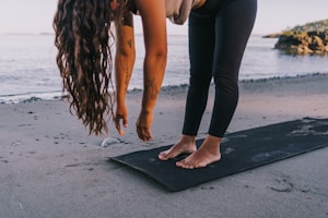 A couple of women standing on top of a yoga mat