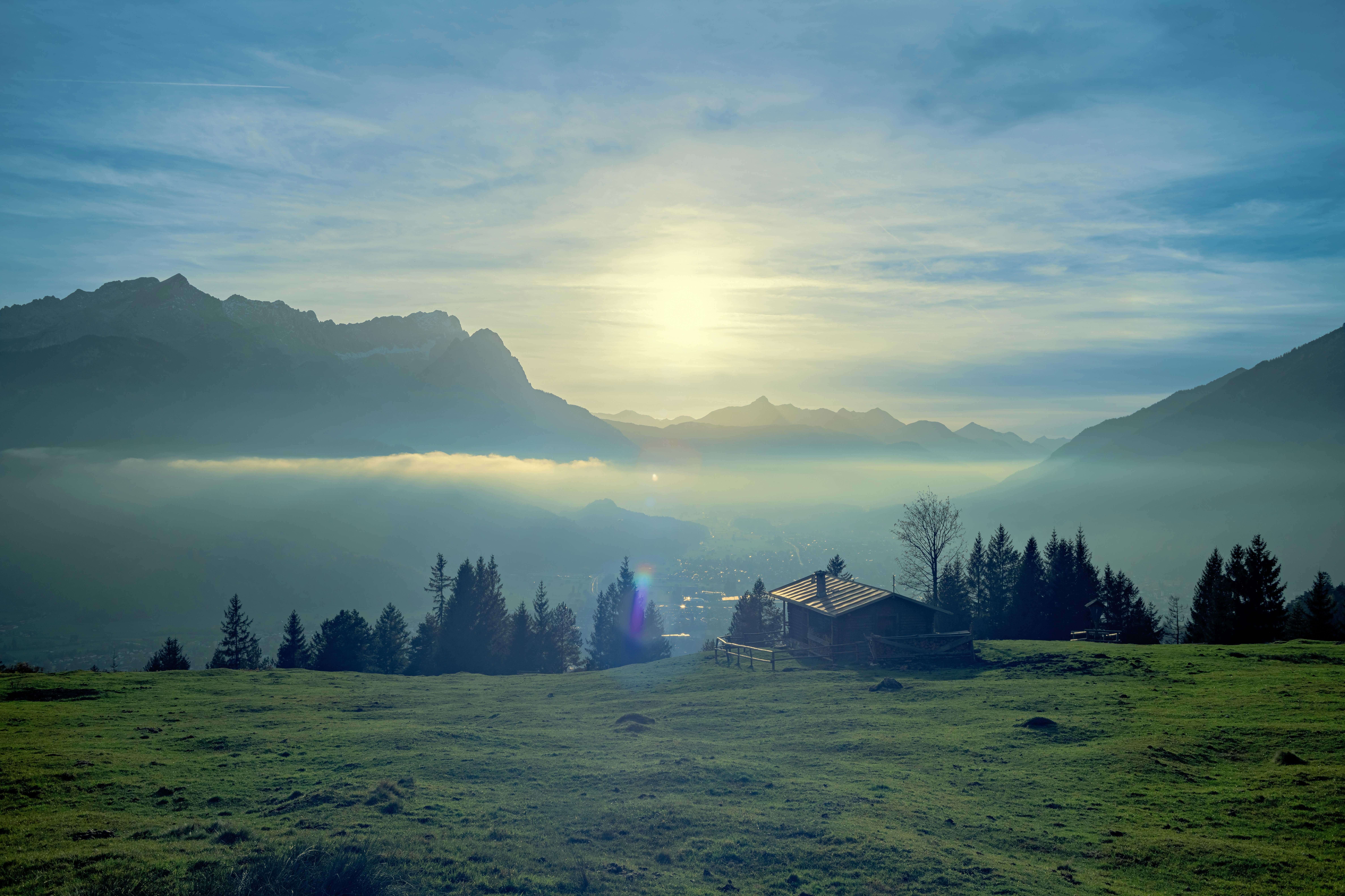 A field with a house and mountains in the background