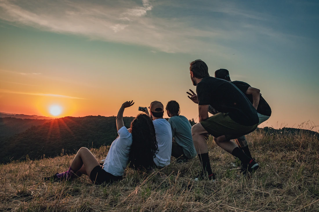 Friends watching the sunset from a grassy hilltop