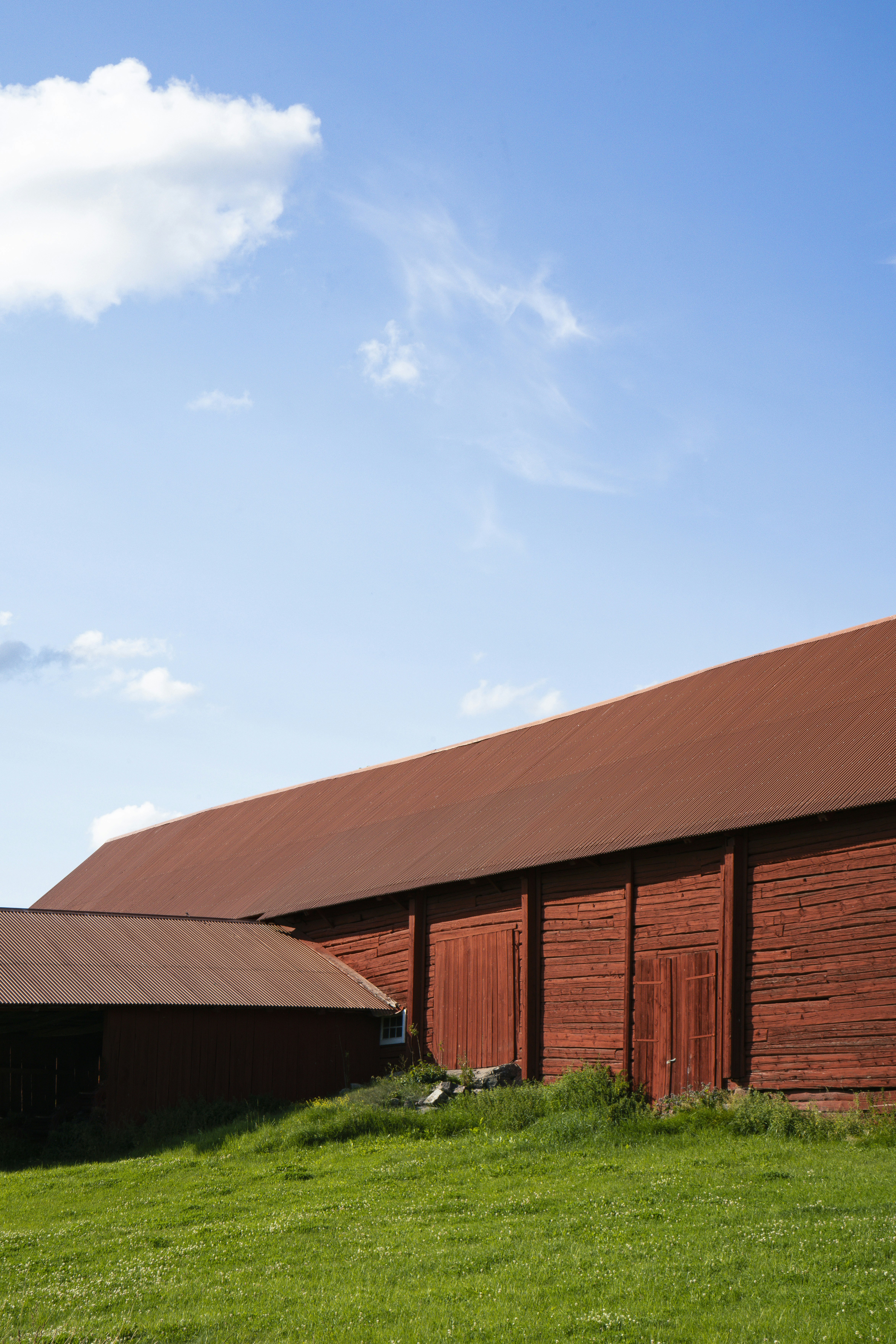 A large red barn sitting on top of a lush green field photo – Free ...