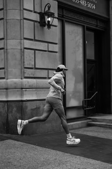 A man running down a street next to a tall building