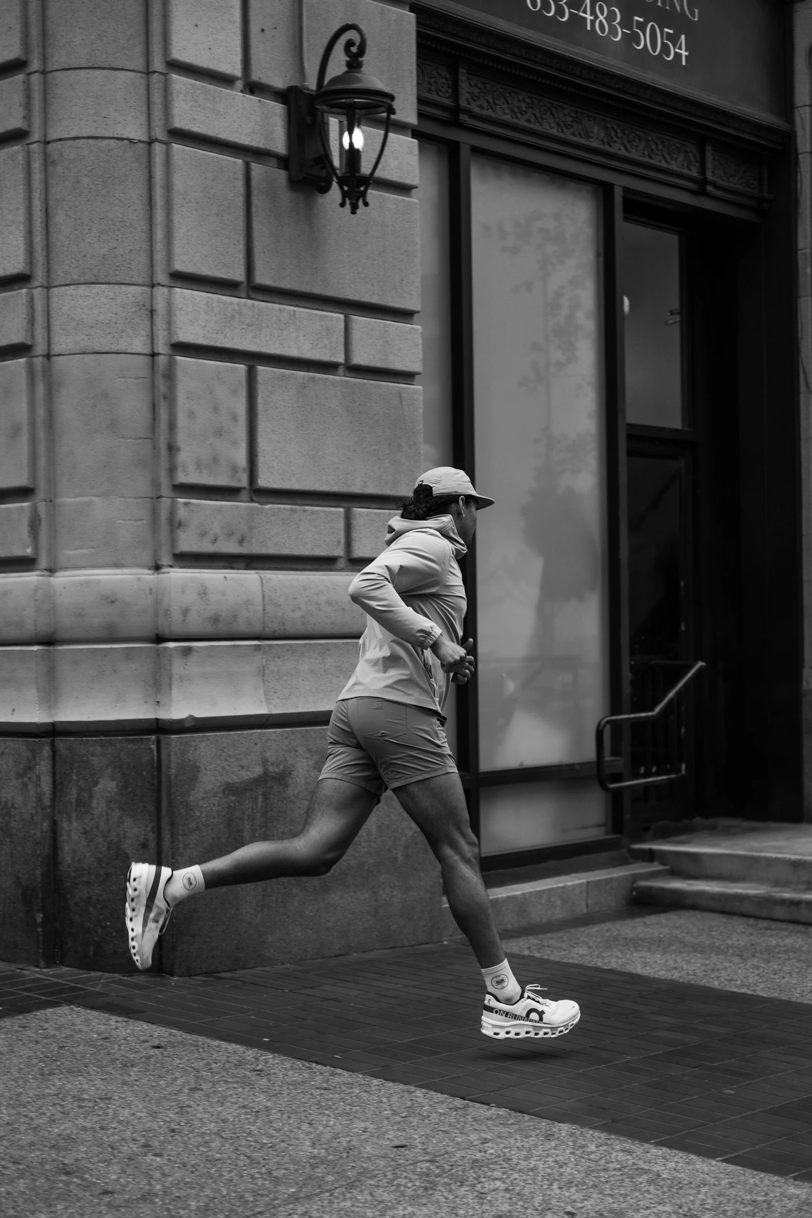 A man running down a city street beside a tall building