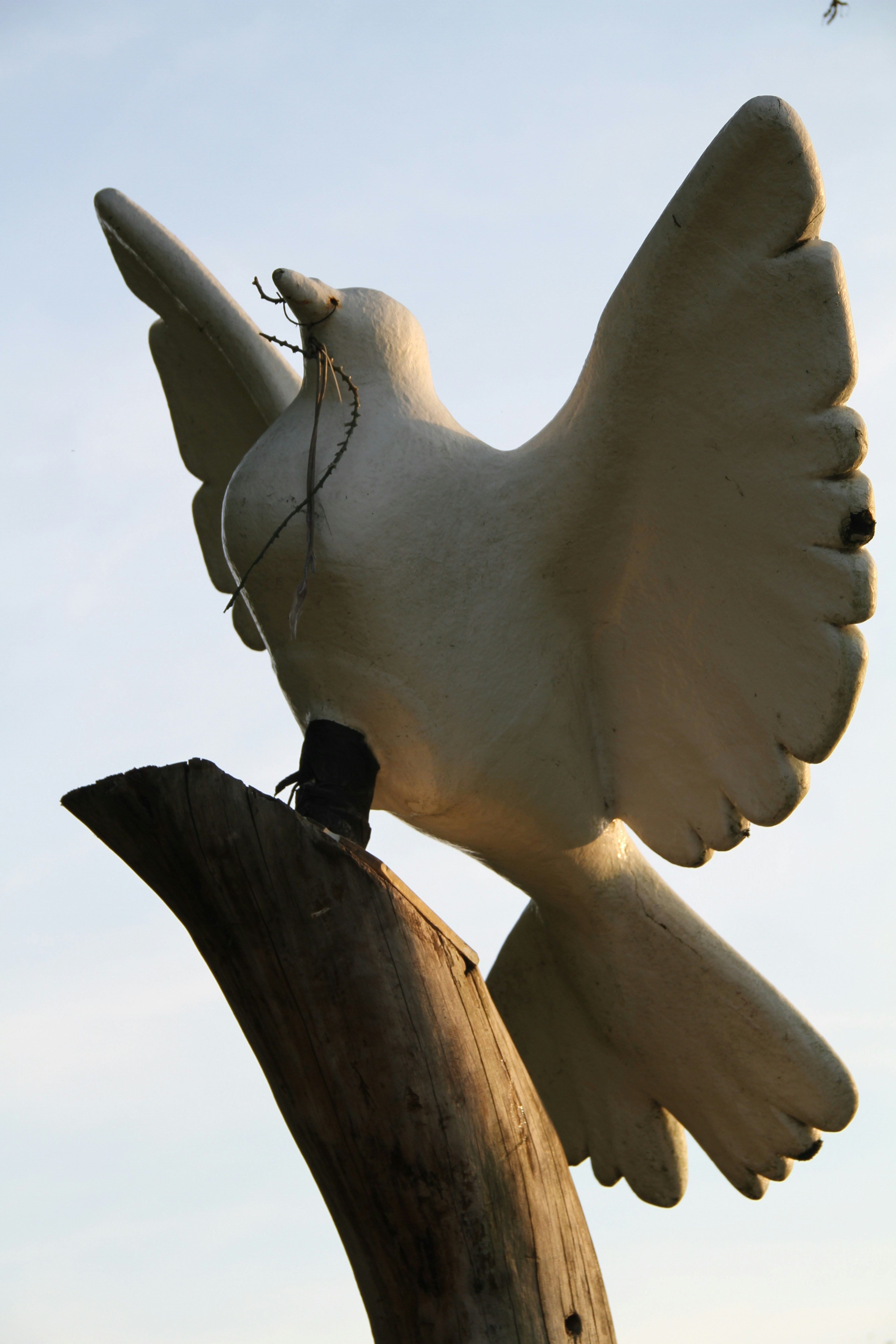 A statue of a bird on top of a wooden pole