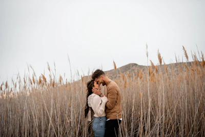 A man and a woman standing in a field of tall grass