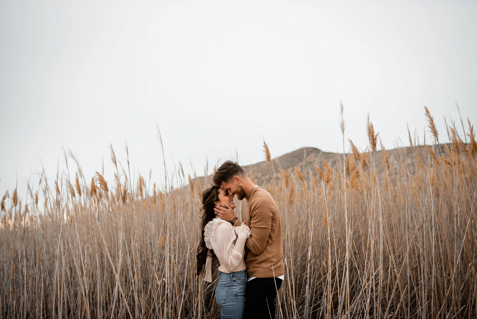 A couple kissing in a meadow of tall dry grass
