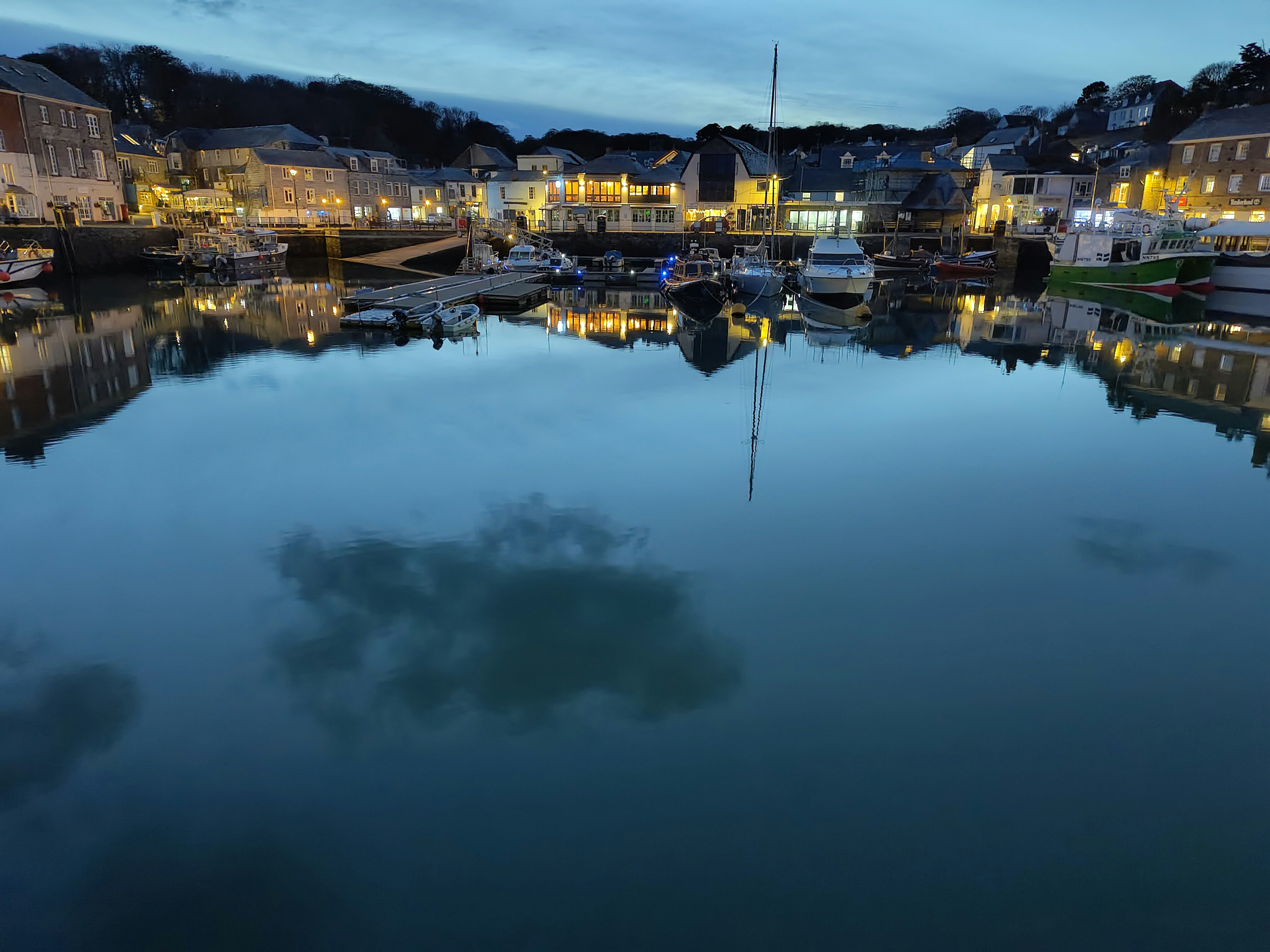 Alicante harbour at dusk with moored boats, warm amber sky, deep water reflections, low-key maritime atmosphere
