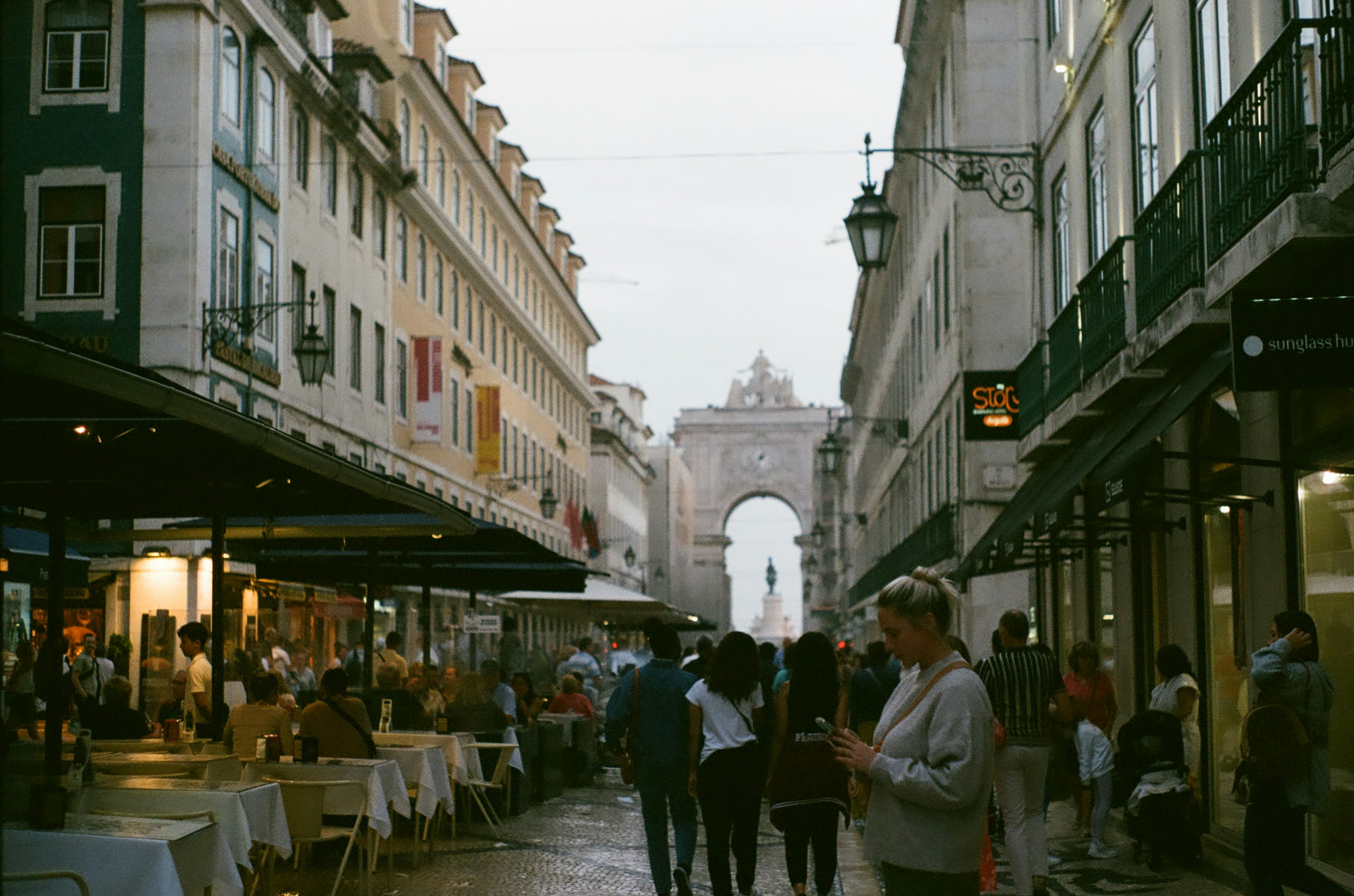 A group of people walking down a street next to tall buildings