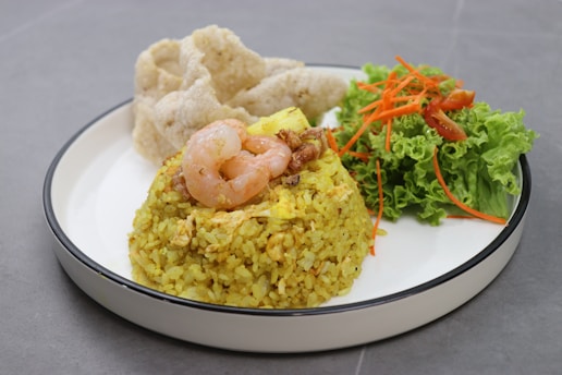 A white plate topped with rice and shrimp