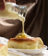 A person pouring a sauce on a piece of bread