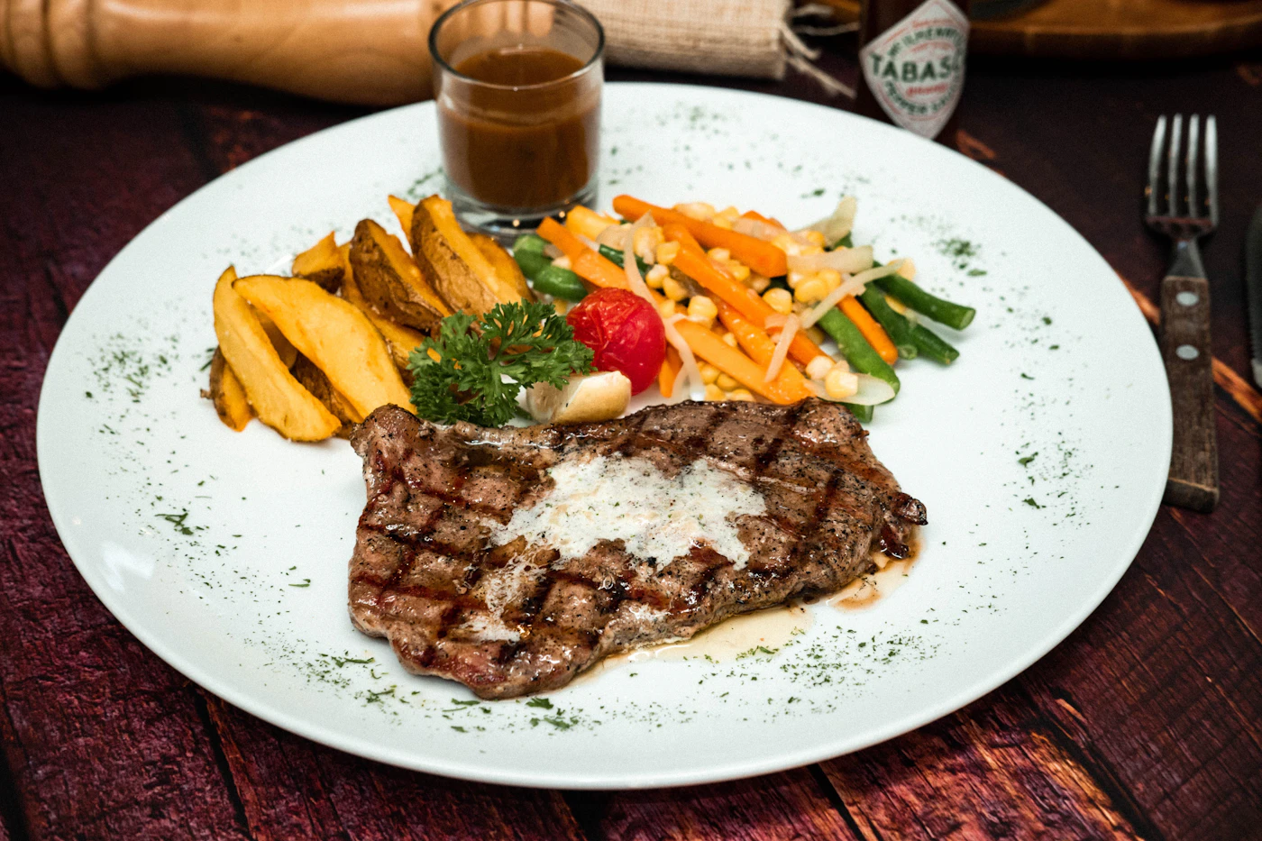 Sliced steak with roasted potato wedges, vegetables, and a savory pan sauce