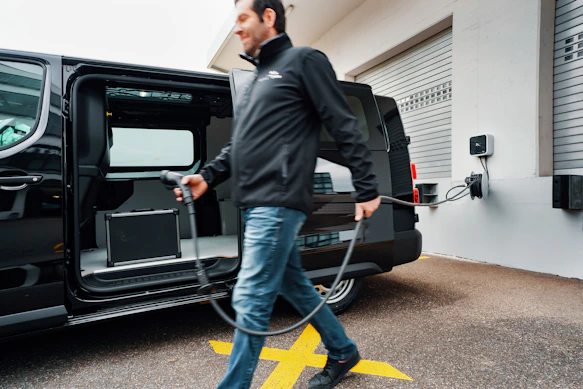 A man walking a dog in front of a black van