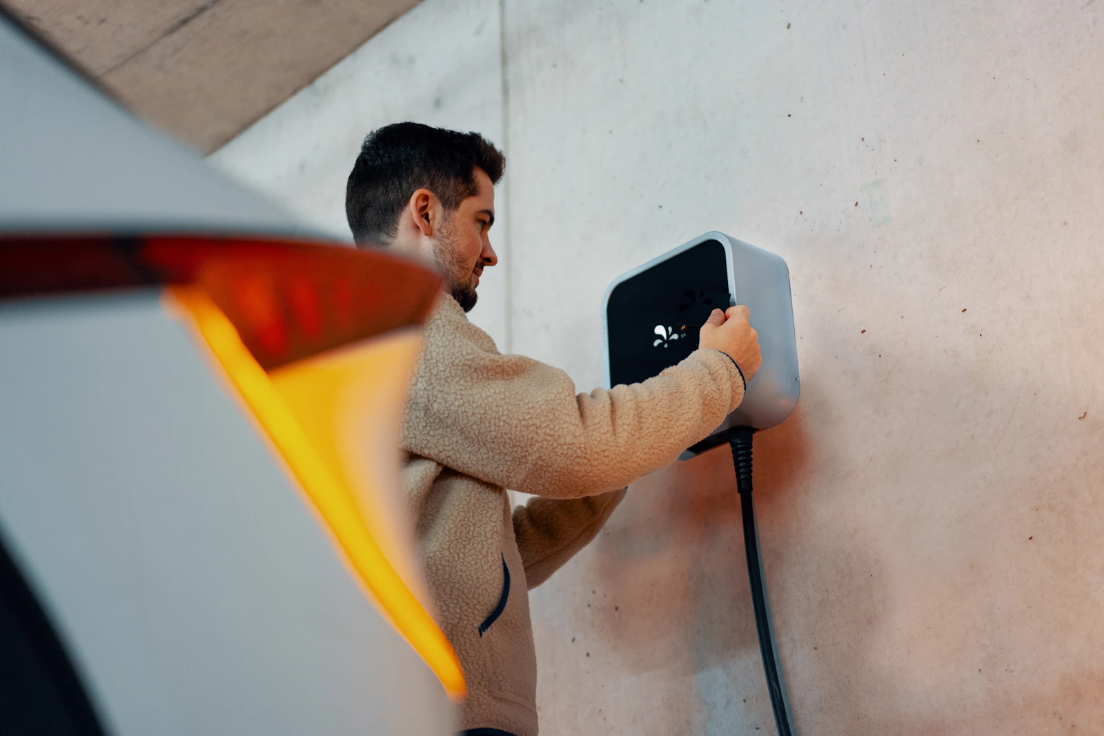 Electrician mounting a Level 2 EV charging unit on a garage wall