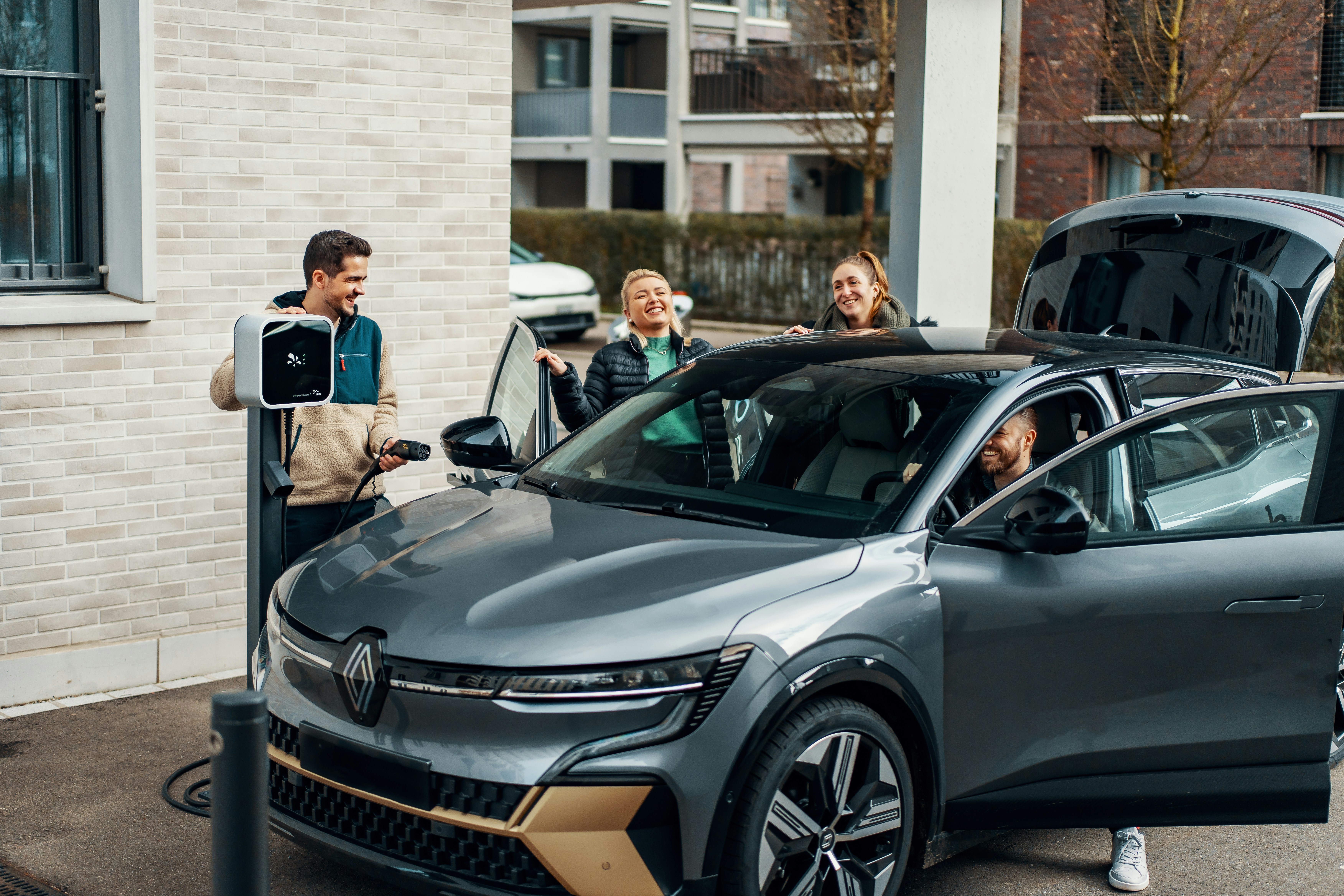 A group of people standing around a silver car