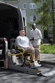A man sitting in a wheelchair next to a van