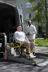 A man sitting in a wheelchair next to a van