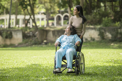 A woman in a wheelchair standing next to a man in a park